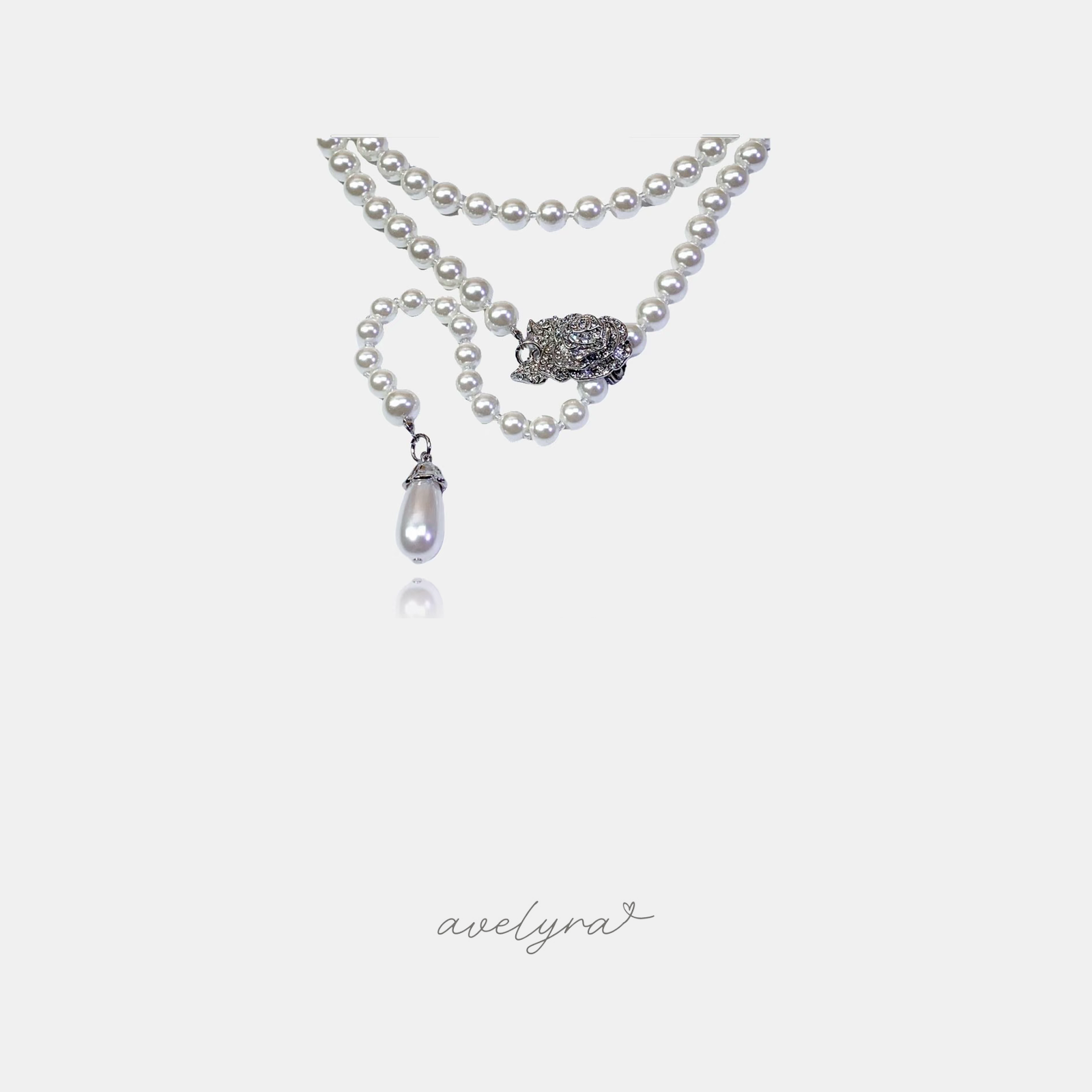 White pearl bead necklace with a crystal-set silver-tone ornamental clasp and a teardrop pearl drop pendant.