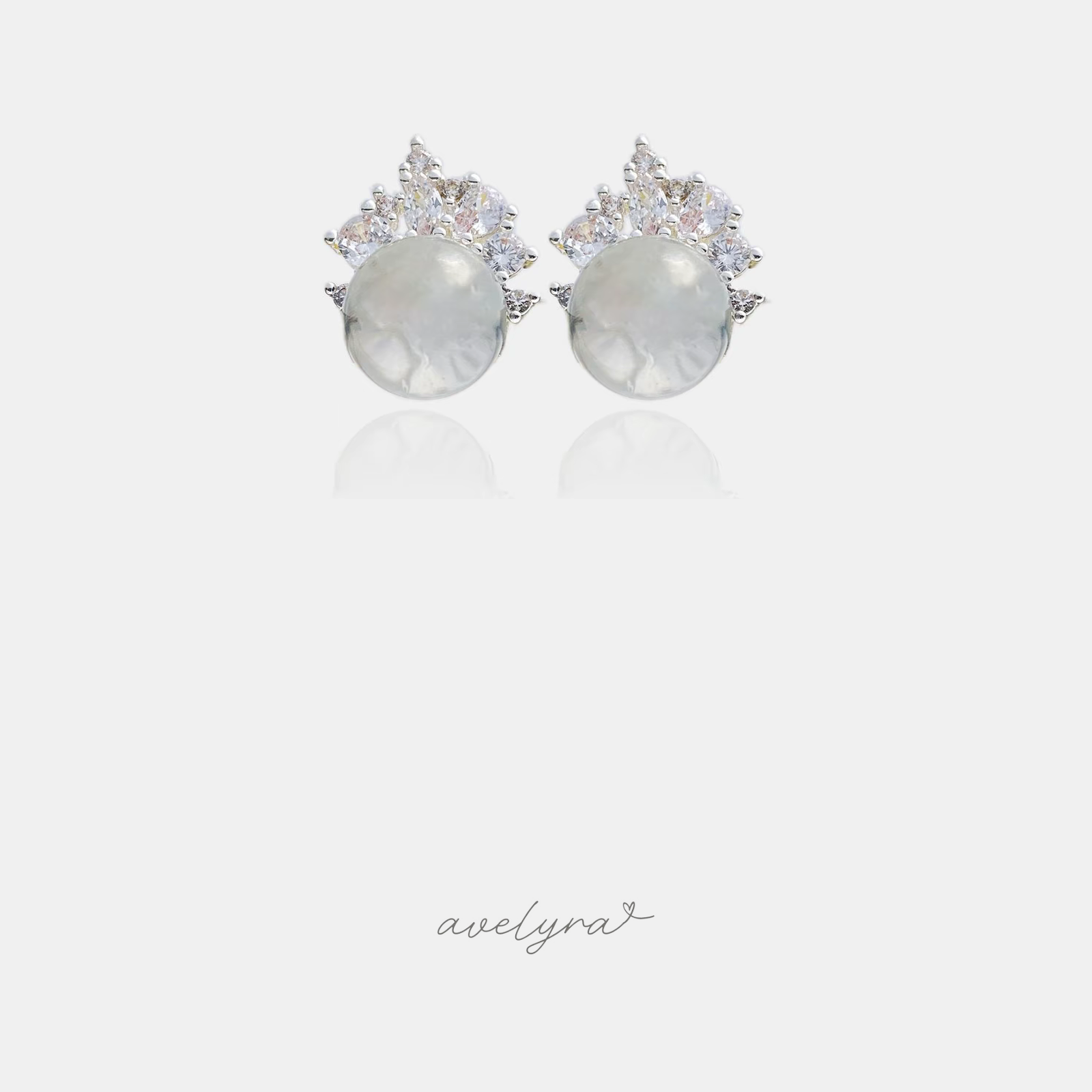 Stud earrings with a round white dome below a fan of clear crystal stones.