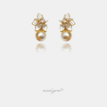Gold-tone earrings with a white pearlescent petal flower and crystal centre above a golden round pearl.