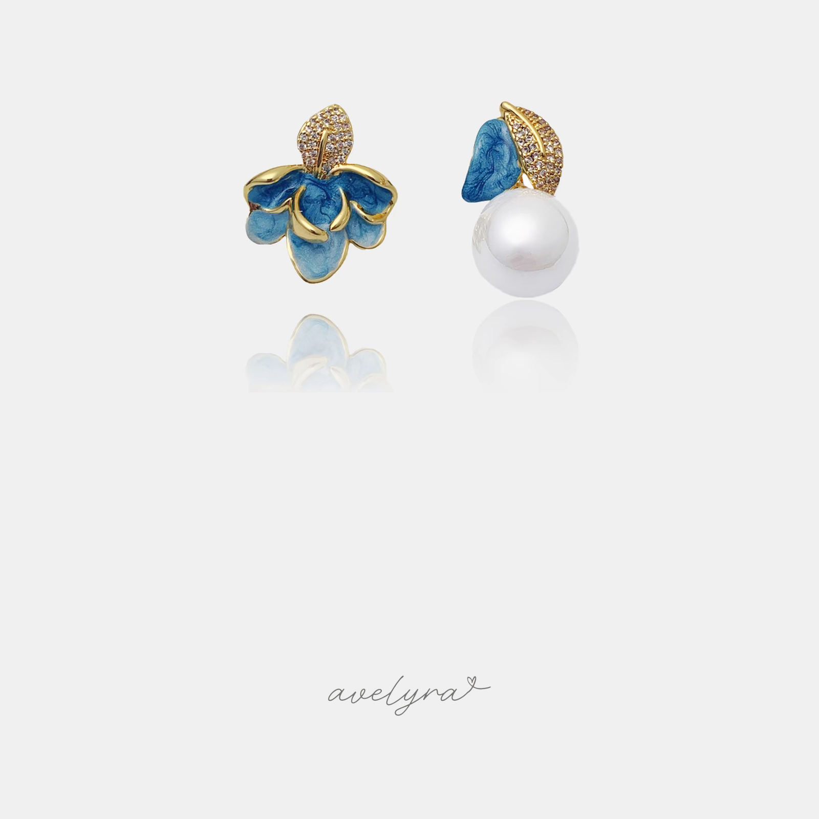 Mismatched gold-tone stud earrings: one blue enamel flower with pave leaf, one white pearl with blue petal.