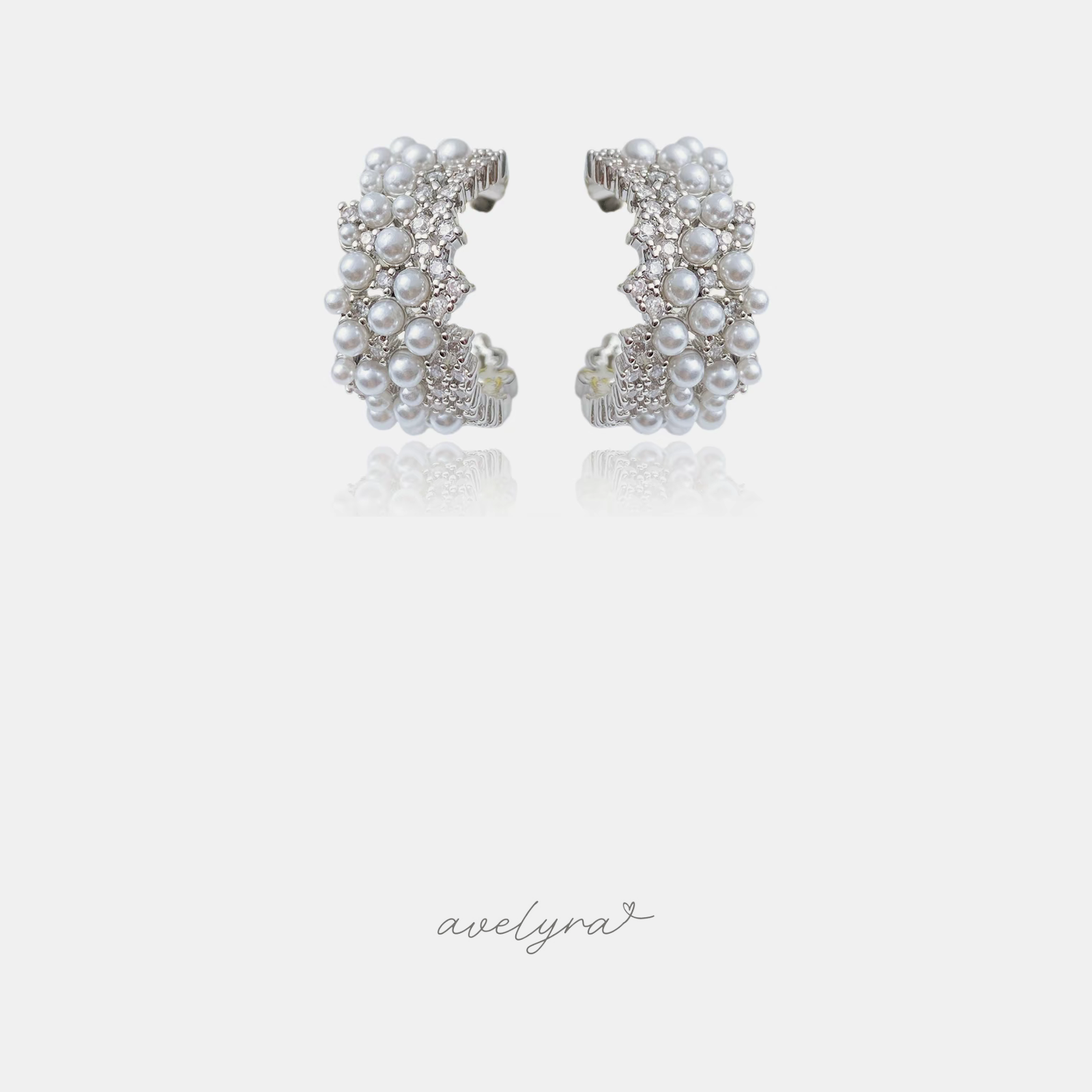 Curved C-shaped hoop earrings encrusted with small white pearls and clear crystals in a silver-tone setting.