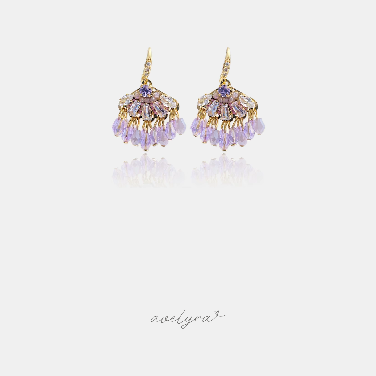 Gold-tone hook earrings with a crystal crest above a fringe of lilac beads.