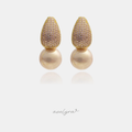 Gold pavé teardrop earrings with blush stones above a large rounded pearl.