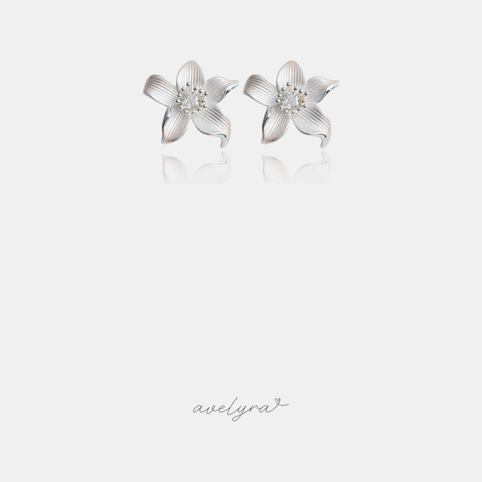 Silver-tone lily flower stud earrings with curved petals and a clear square stone in the centre.