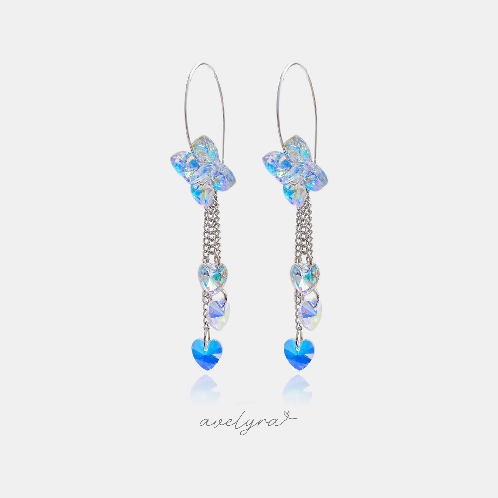 Pair of silver-tone hook earrings with an iridescent butterfly and chains holding heart-shaped crystals ending in a blue heart stone.