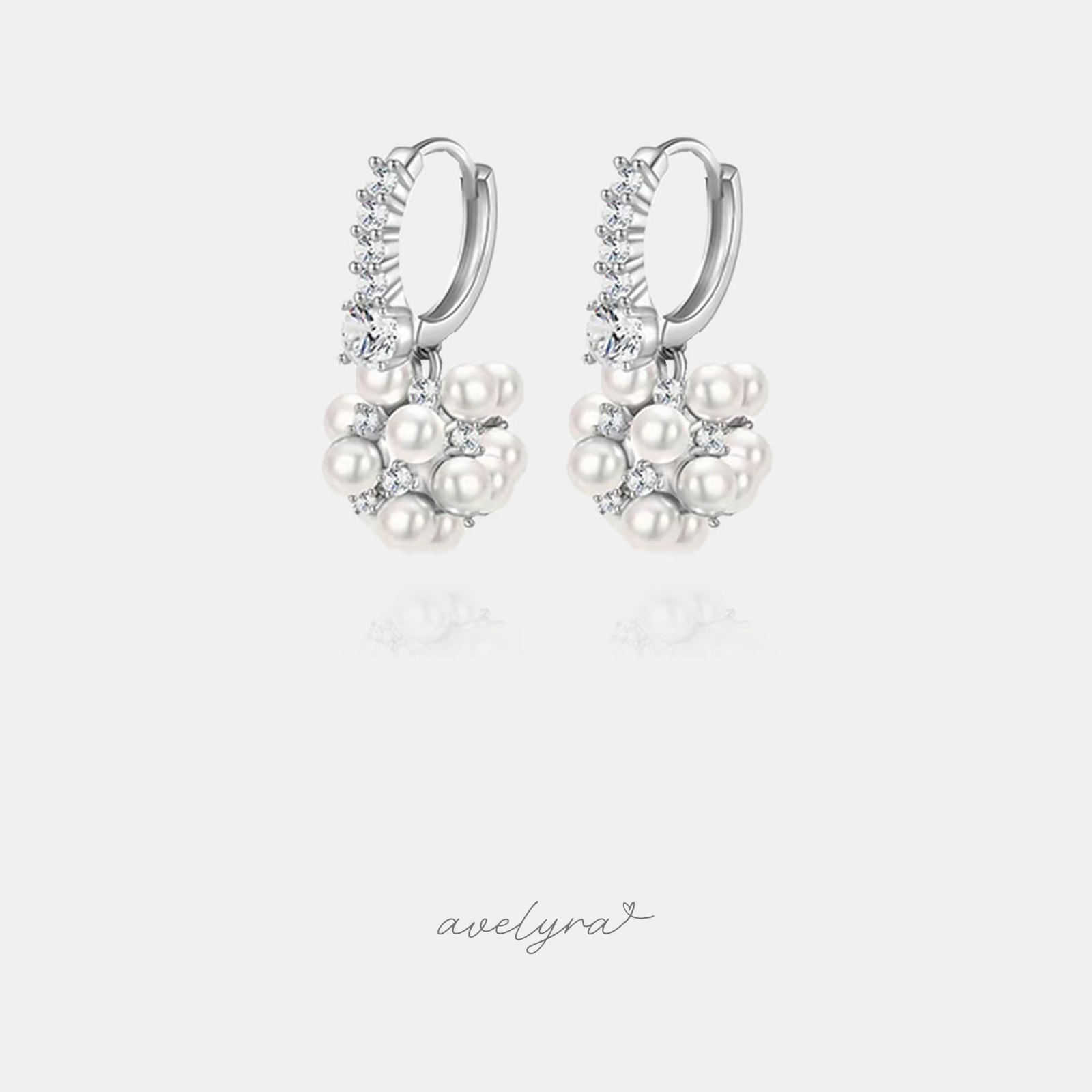 Pair of silver-tone huggie hoop earrings set with clear stones and a cluster of white pearls with small accent stones.