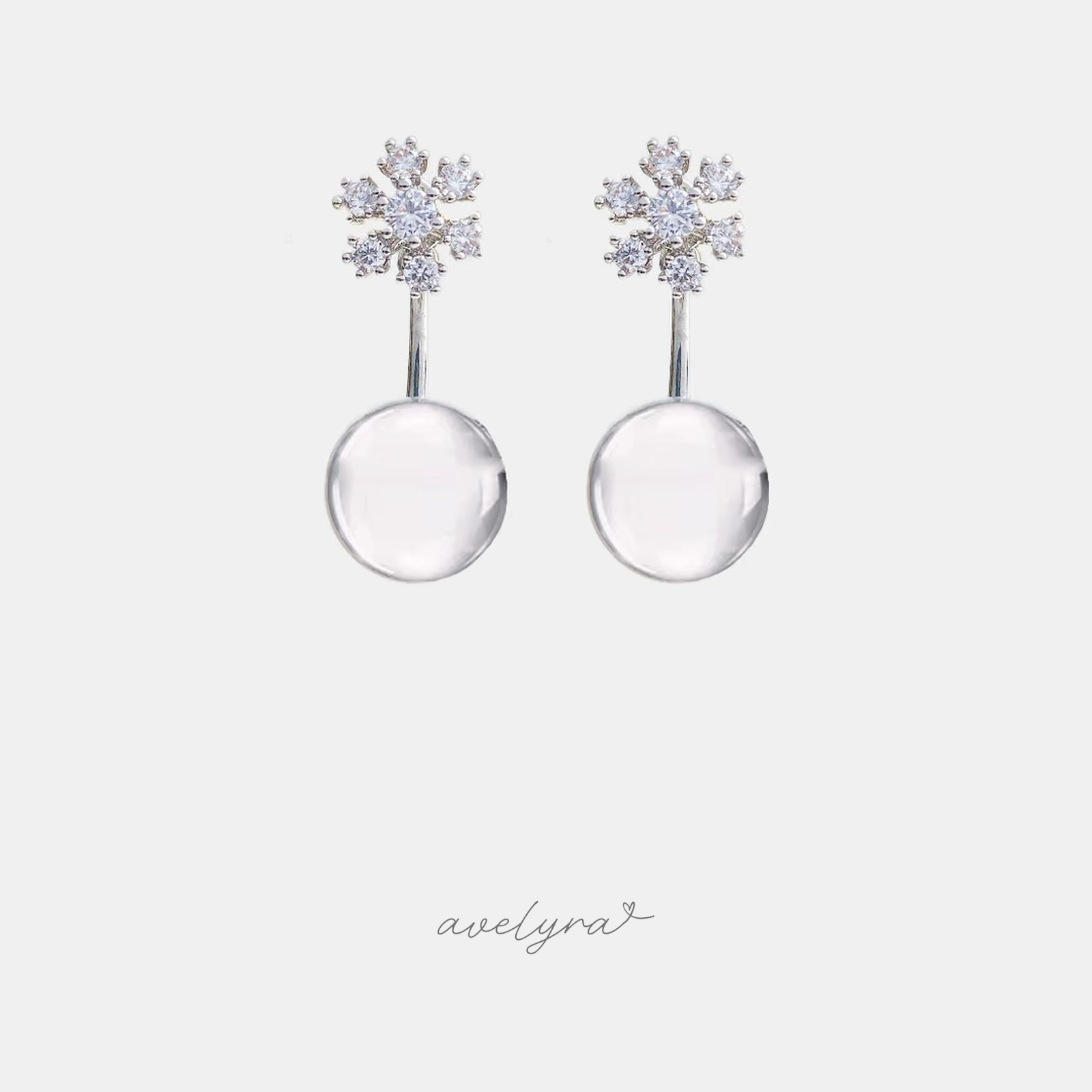 Silver-tone snowflake stud earrings with a clear round drop below.