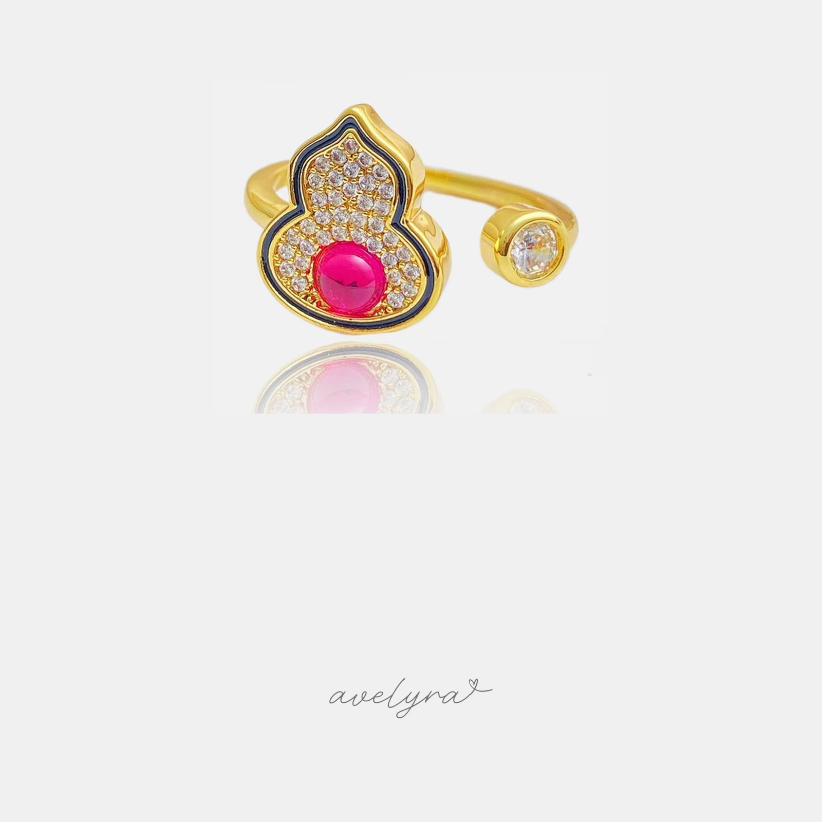 Gold-tone open ring shaped as a pave gourd with a red centre stone and a small clear stone on the other end