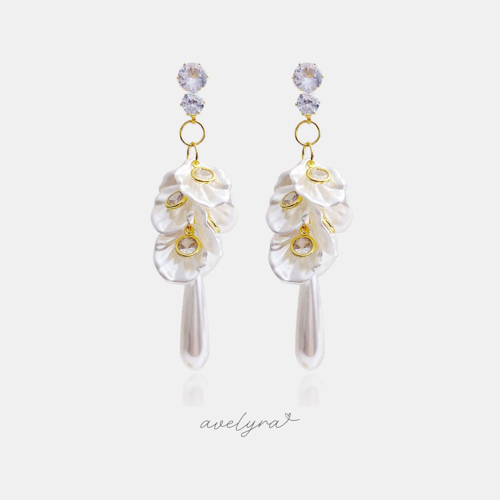 Gold-tone drop earrings with two clear crystals above ruffled white pearlescent petals, gold-framed crystals, and a long teardrop pearl.