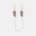 Gold-tone threader earrings with a cluster of green and purple faceted beads and a pale crystal, on long fine chains.