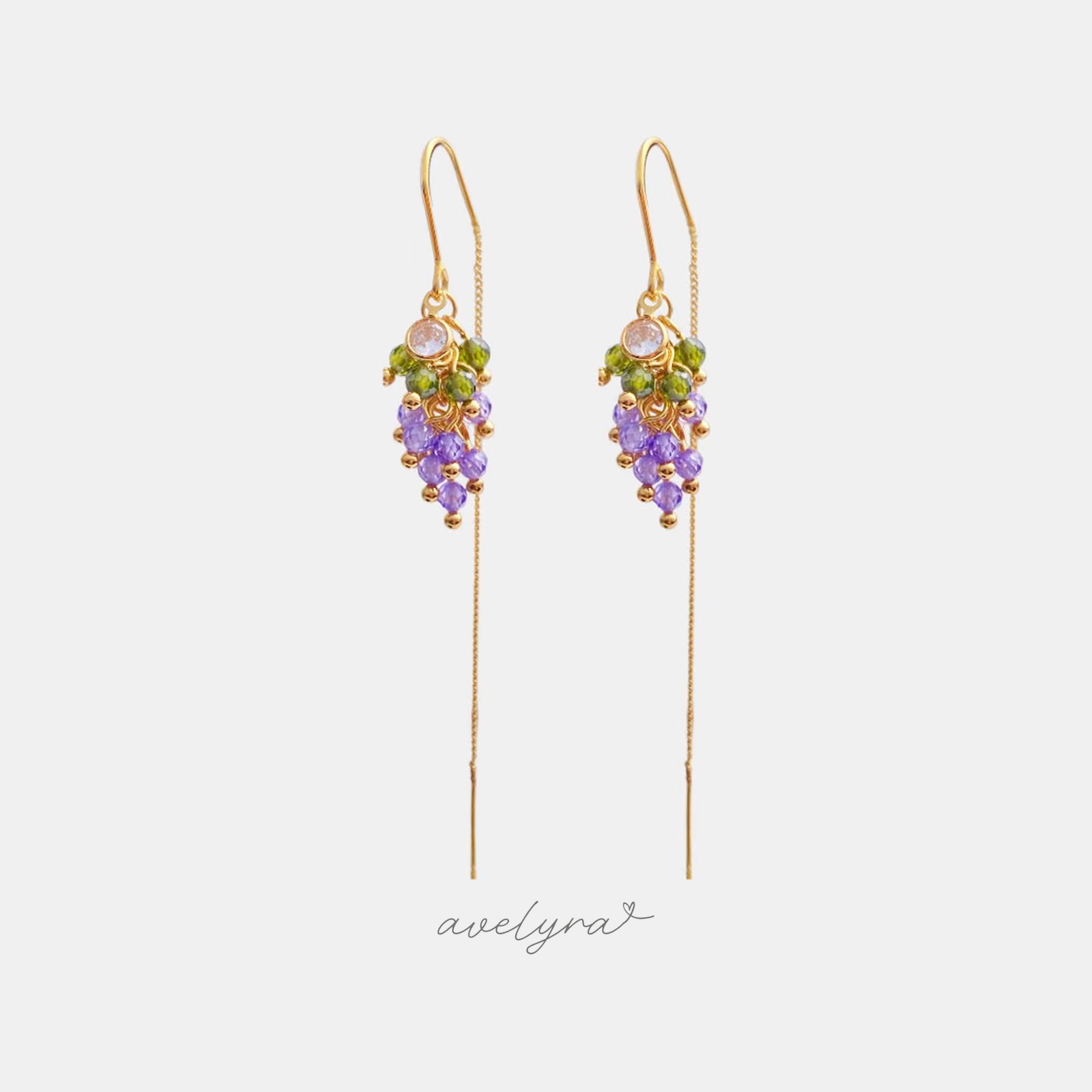 Gold-tone threader earrings with a cluster of green and purple faceted beads and a pale crystal, on long fine chains.