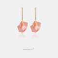 Gold-tone earrings with a vertical bar of clear baguette crystals holding a sculptural blush-pink curled petal.