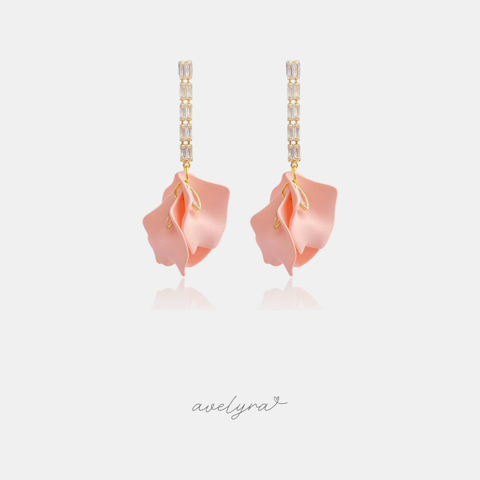 Gold-tone earrings with a vertical bar of clear baguette crystals holding a sculptural blush-pink curled petal.