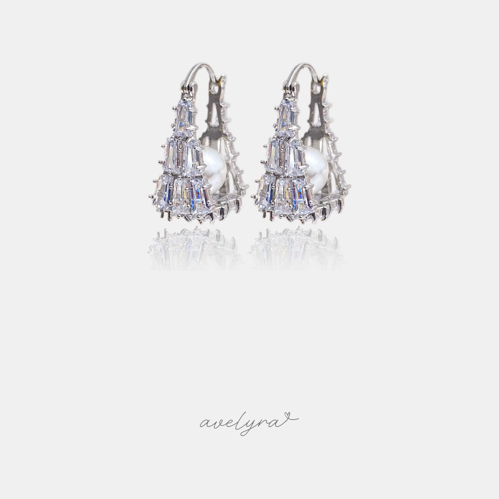 Silver-tone huggie earrings encrusted with crystals cradling a central pearl