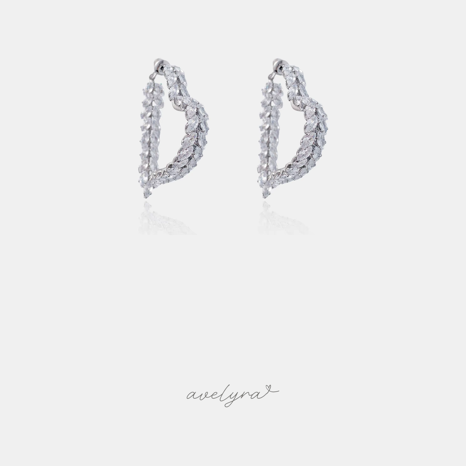 Silver-tone heart-shaped hoop earrings lined with clear marquise-cut crystals.