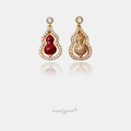 Pair of gourd-shaped gold drop earrings outlined in crystals, one with a red stone centre.