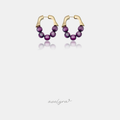 Pair of gold hoop earrings strung with round glossy purple beads.