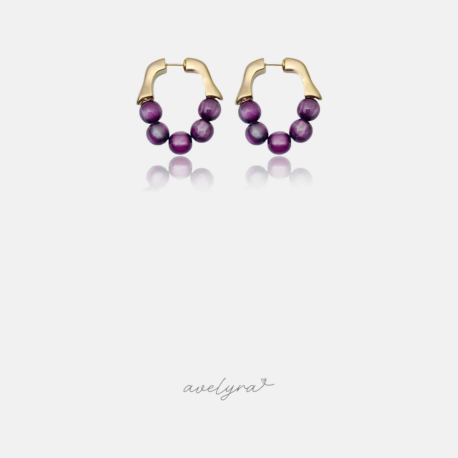 Pair of gold hoop earrings strung with round glossy purple beads.