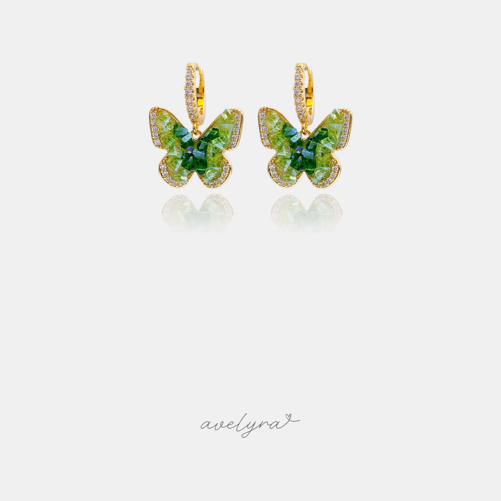 Green faceted butterfly charms edged with clear crystals, suspended from small pave gold-tone huggie hoops.