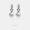 Drop earrings with a large white pearl suspended below a pave crystal ring and huggie hoop top.