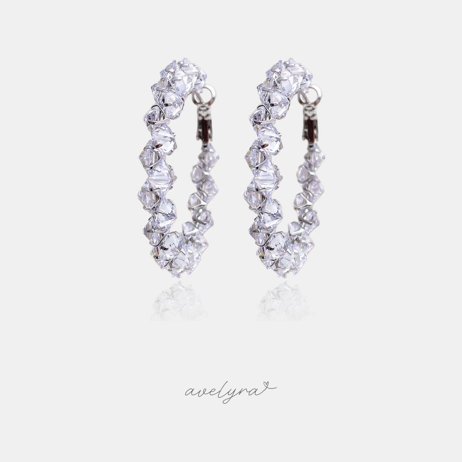 Silver-tone hoop earrings set with clustered clear faceted crystals.
