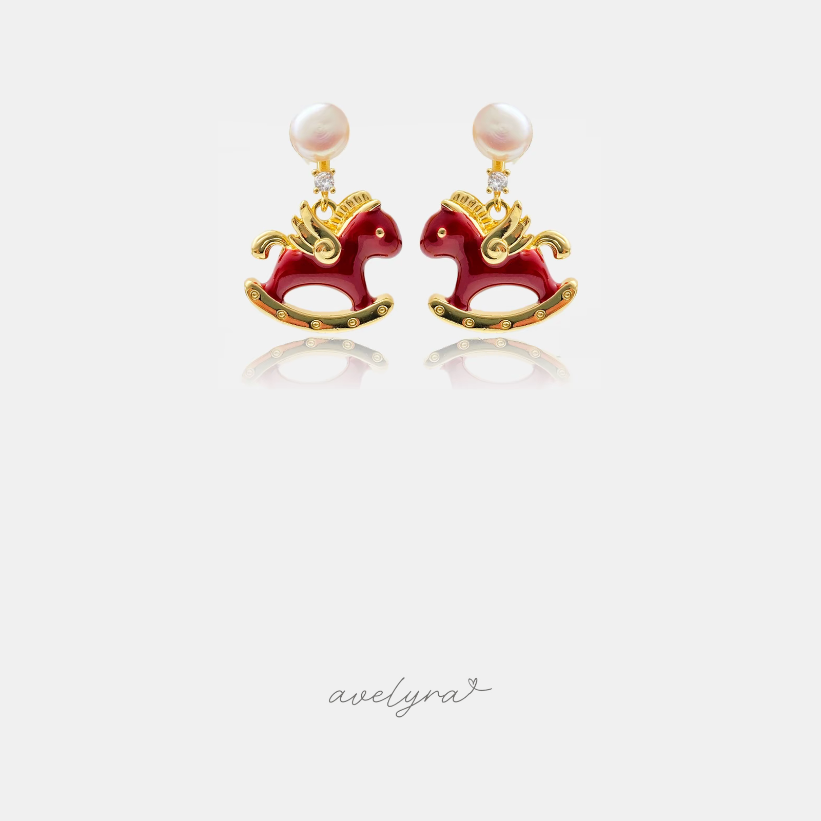 Earrings with a pearl top, small crystal and a red enamel gold-trimmed rocking horse charm.