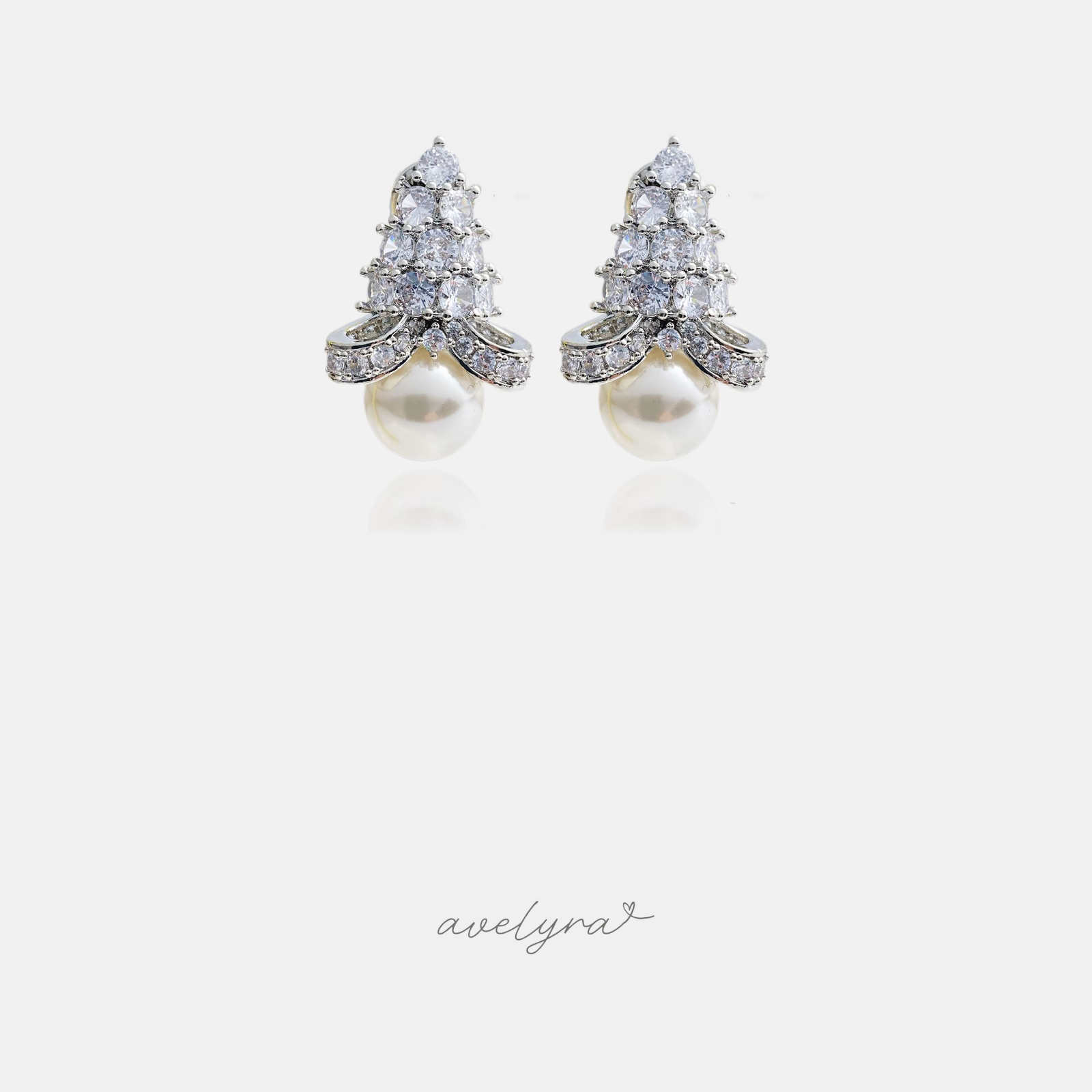 Silver-tone earrings with a tapered cluster of clear crystals above a single white pearl drop.
