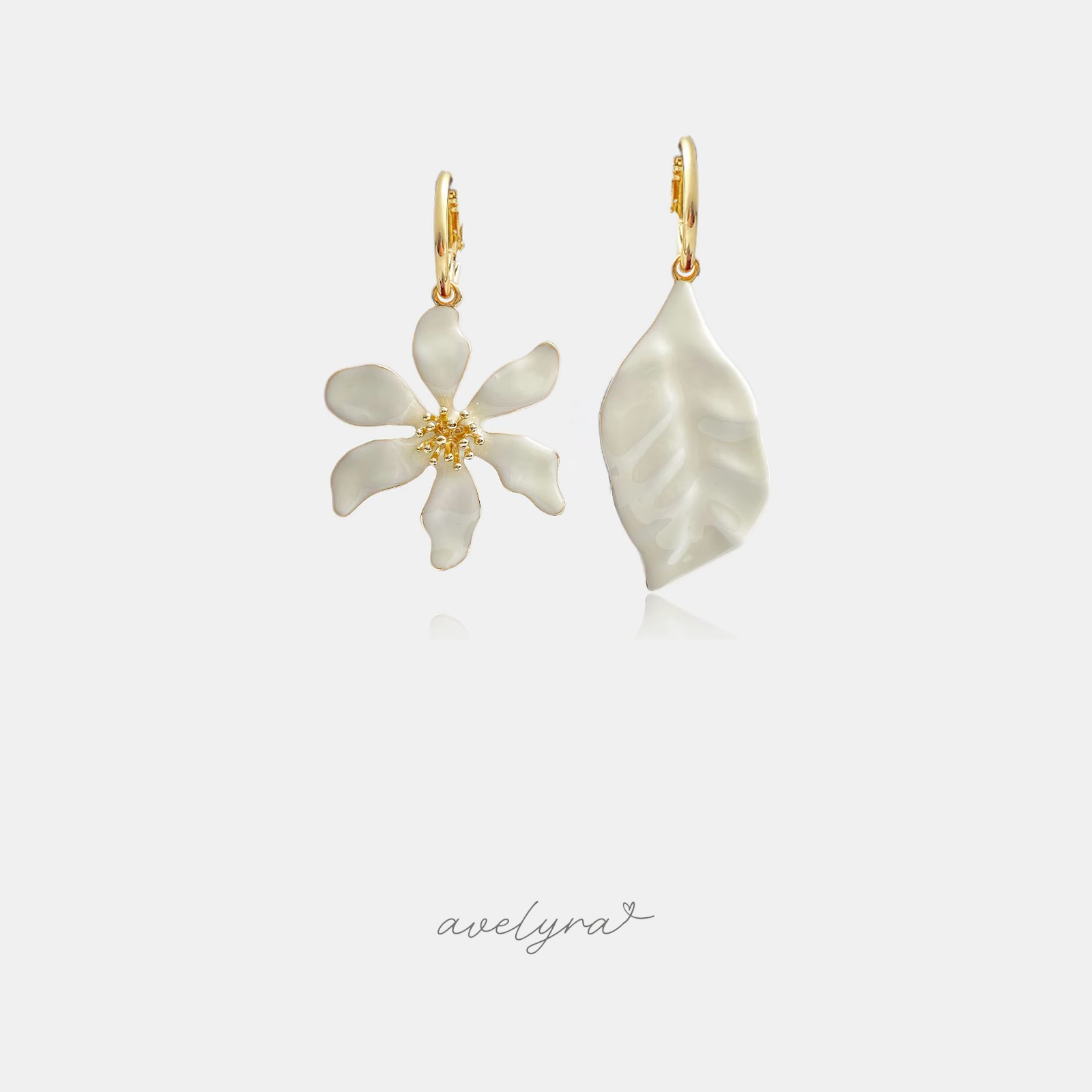 Mismatched drop earrings, one ivory flower and one ivory leaf, on gold-tone huggie hoops.