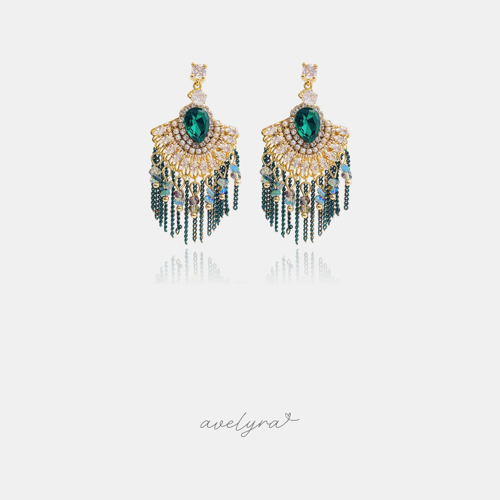 Chandelier earrings with a green pear stone, golden fan of clear stones, and green chain tassels.