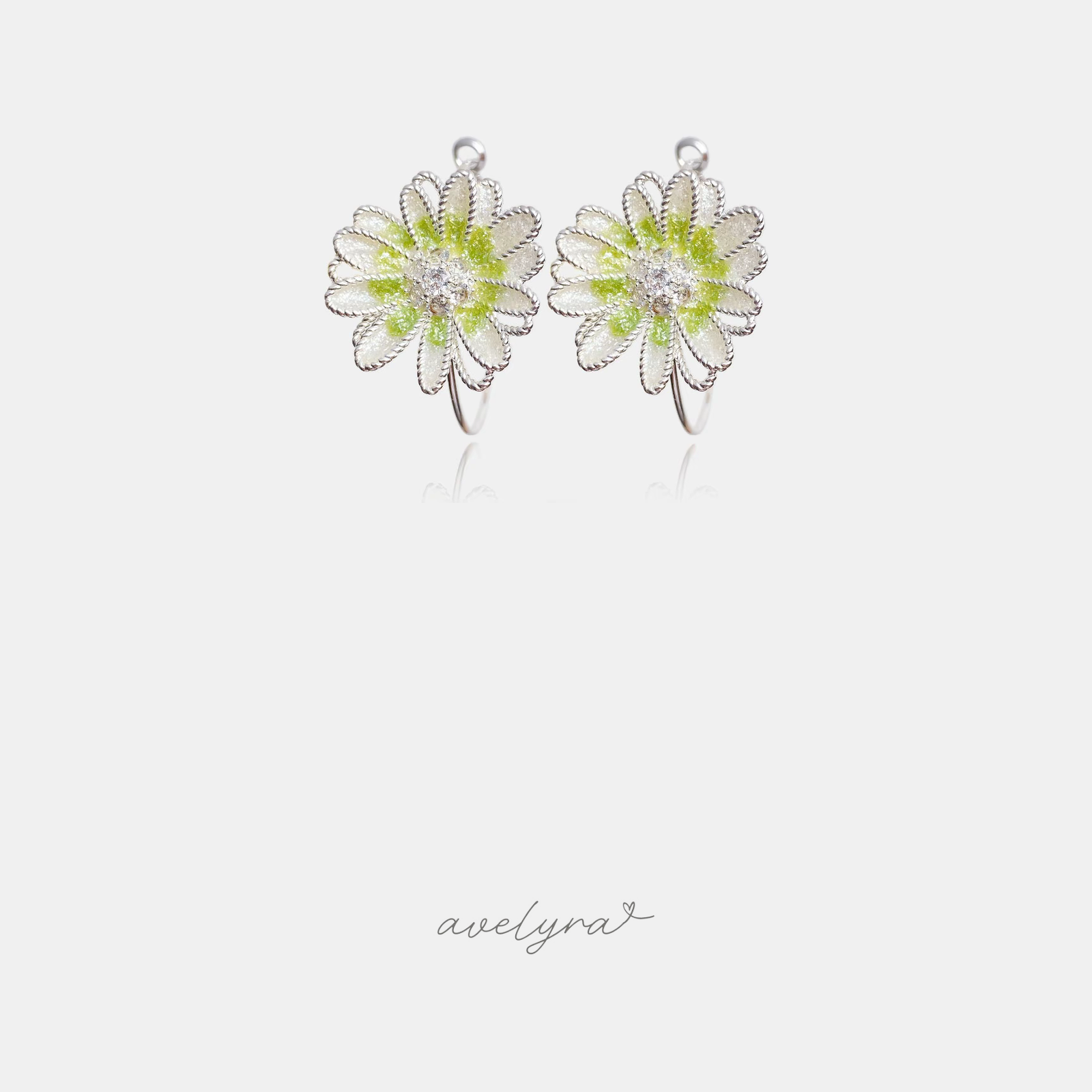 Silver-tone daisy flower earrings with a green centre and clear stone on a thin hoop.
