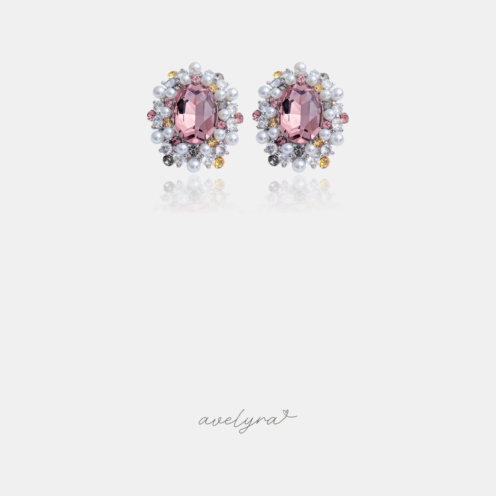 Stud earrings with a mauve-pink oval crystal surrounded by pearls and clear, pink and yellow stones.