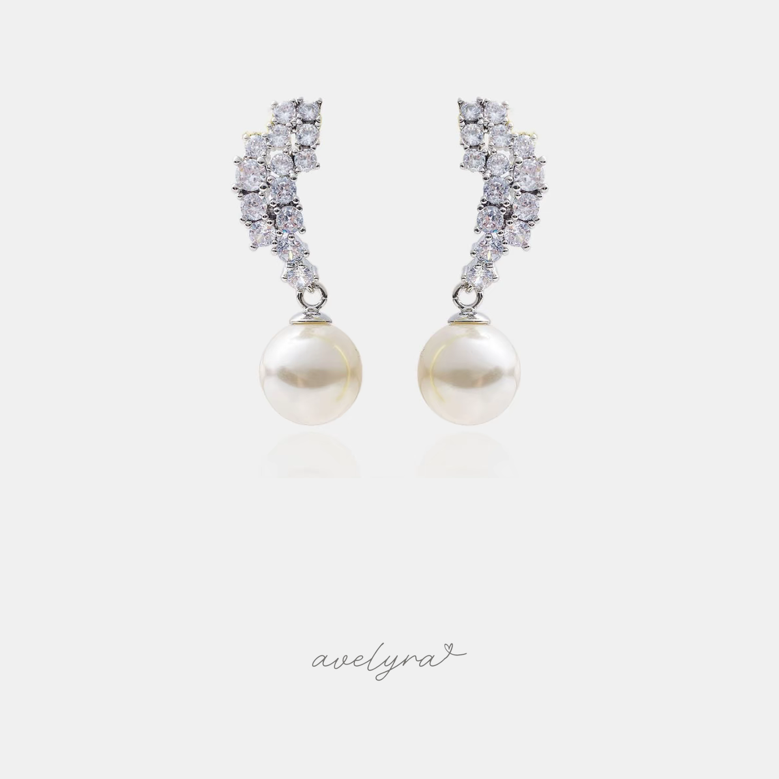Pair of silver-tone drop earrings with a cluster of clear stones sweeping upward above a single round white pearl.