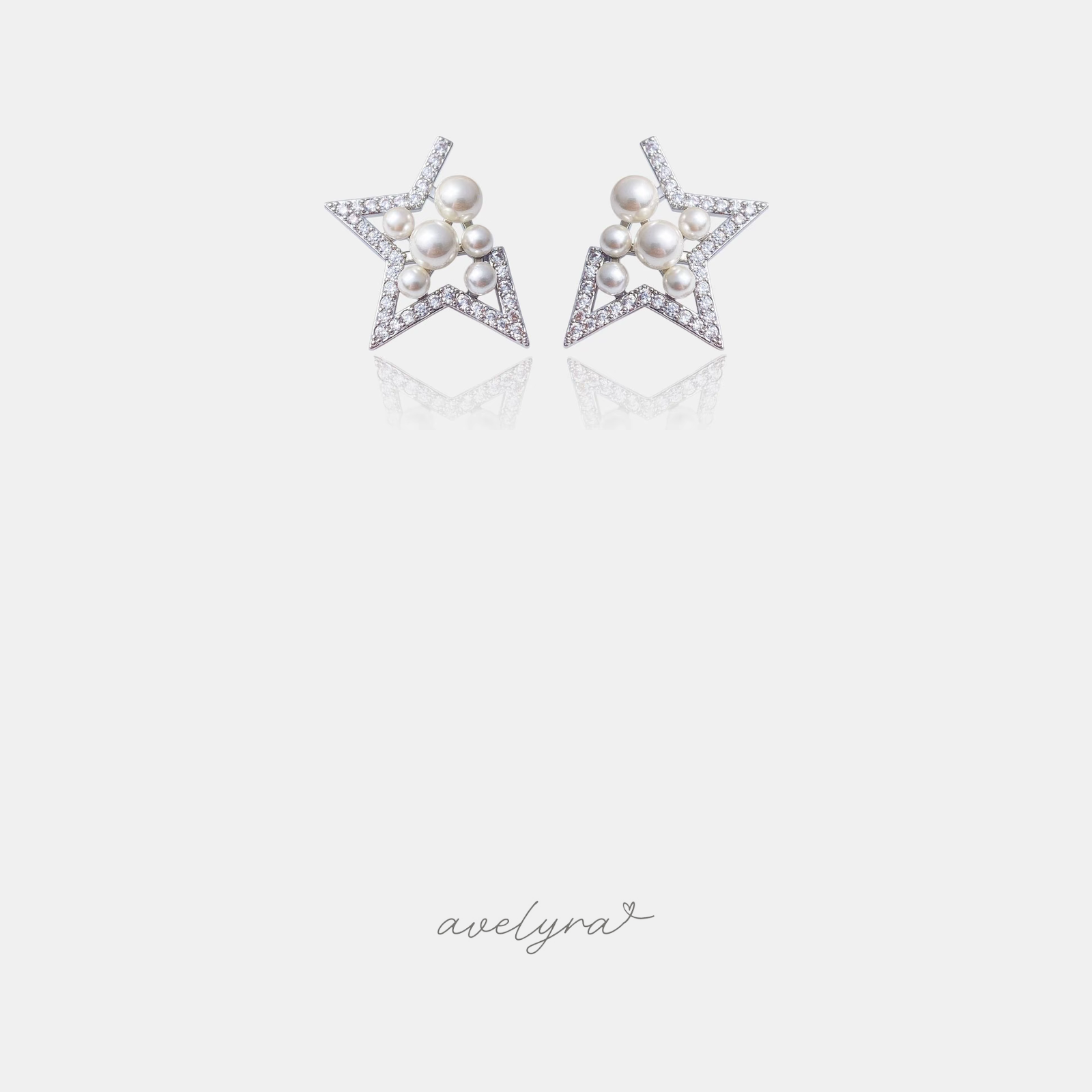 Pair of silver-tone open star stud earrings outlined in clear stones with a cluster of white pearls at the centre.