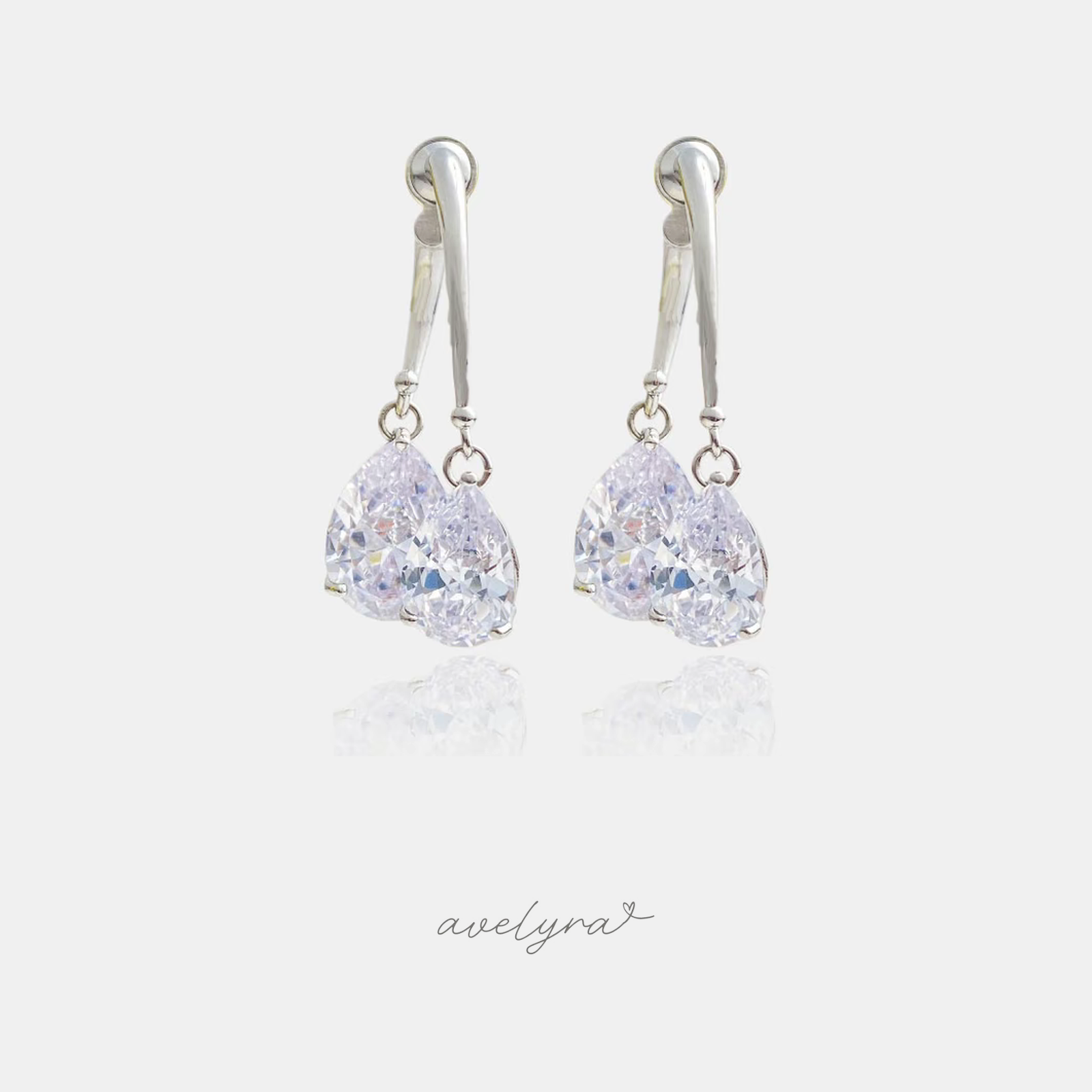 Pair of silver-tone drop earrings each with two clear teardrop-shaped crystals below a polished curved bar.