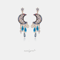 Gold-tone crescent moon earrings set with clear and blue stones and dangling blue crystal droplets.