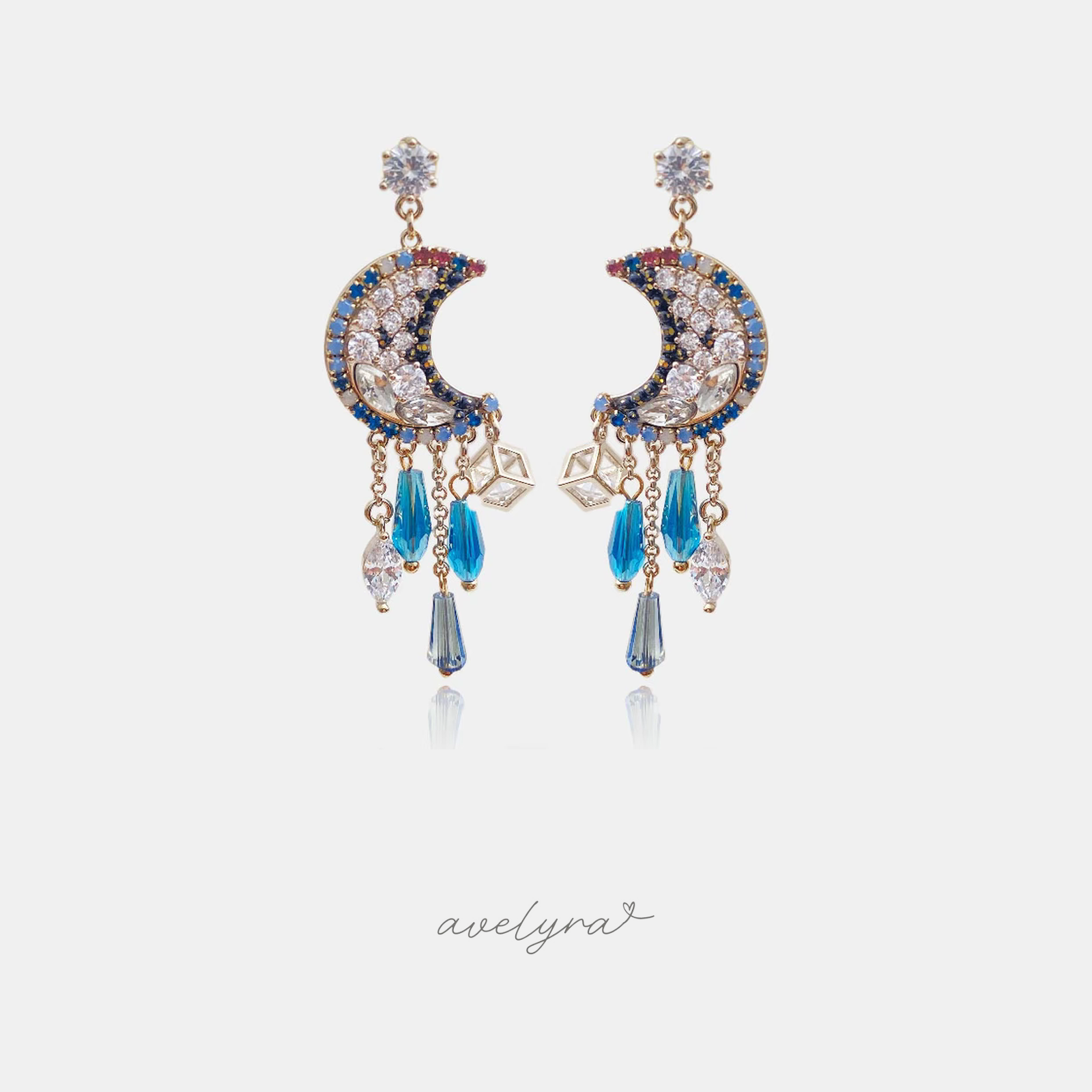 Gold-tone crescent moon earrings set with clear and blue stones and dangling blue crystal droplets.