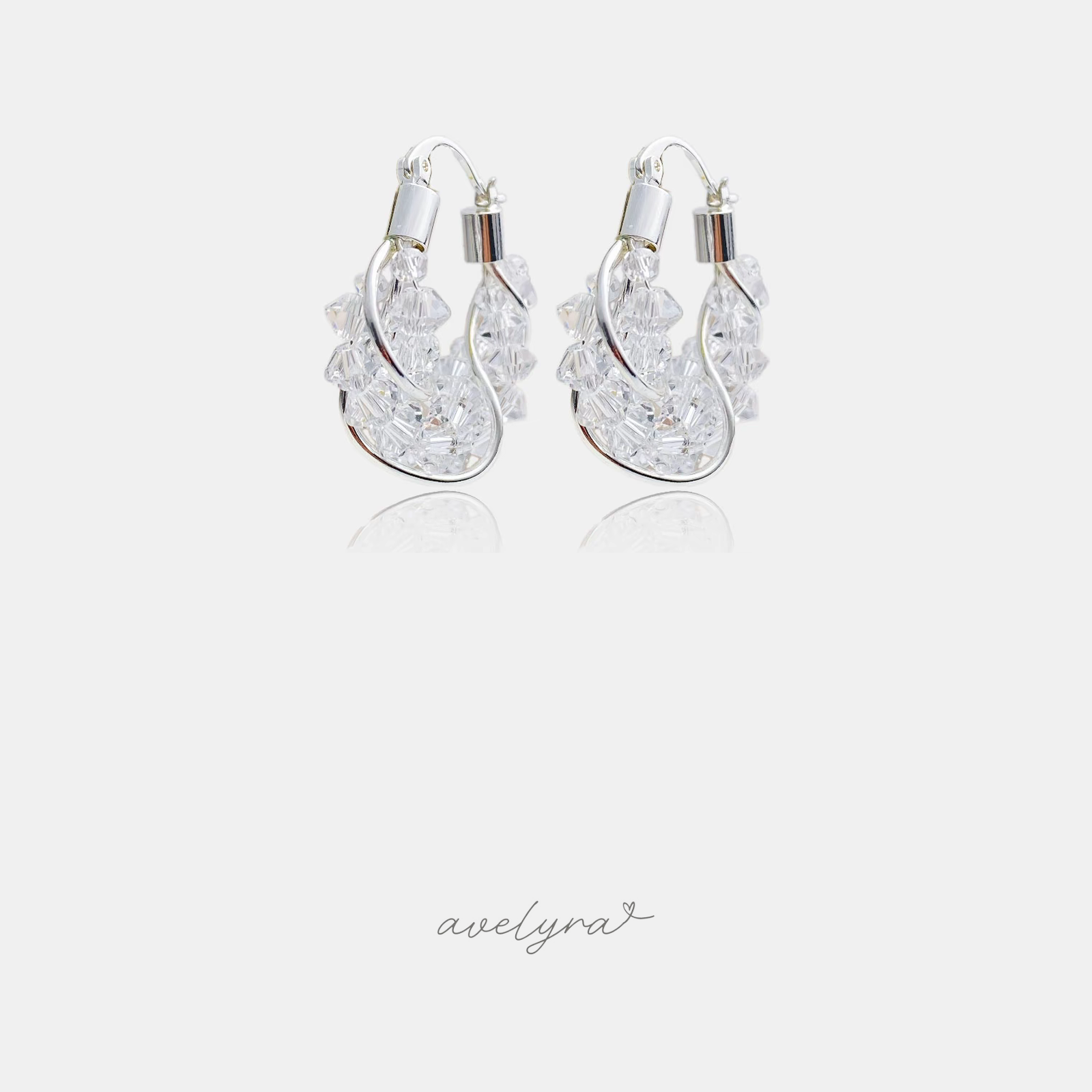 Silver-tone chunky hoop earrings wrapped with clusters of clear faceted crystals.