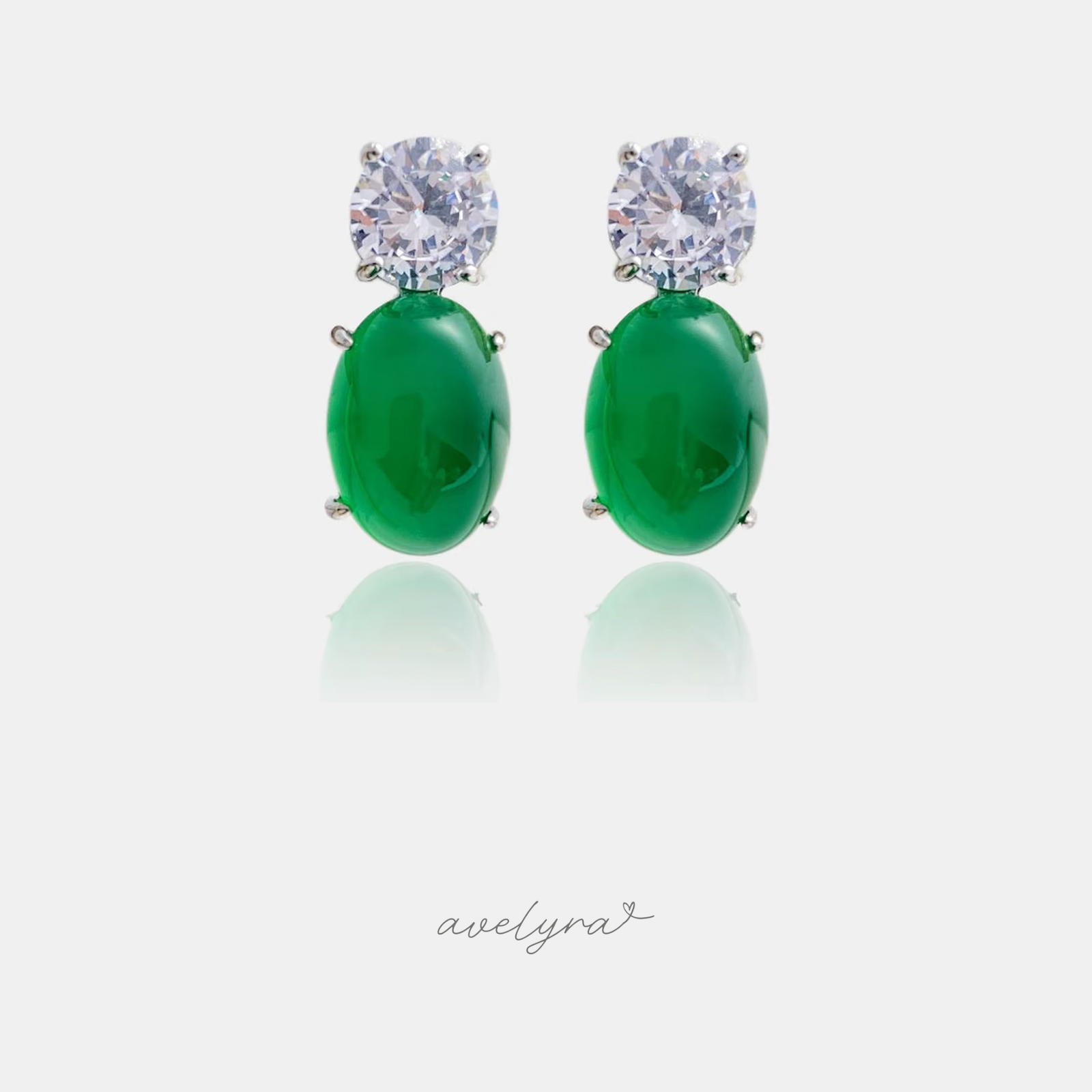 Drop earrings with a clear round stone above a glossy emerald-green oval cabochon in silver-tone prongs.