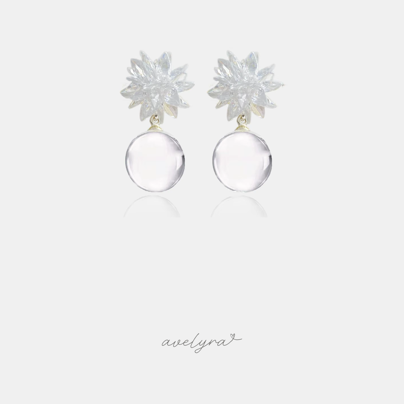 Earrings with a starburst of clear marquise stones above a round clear glass ball drop.