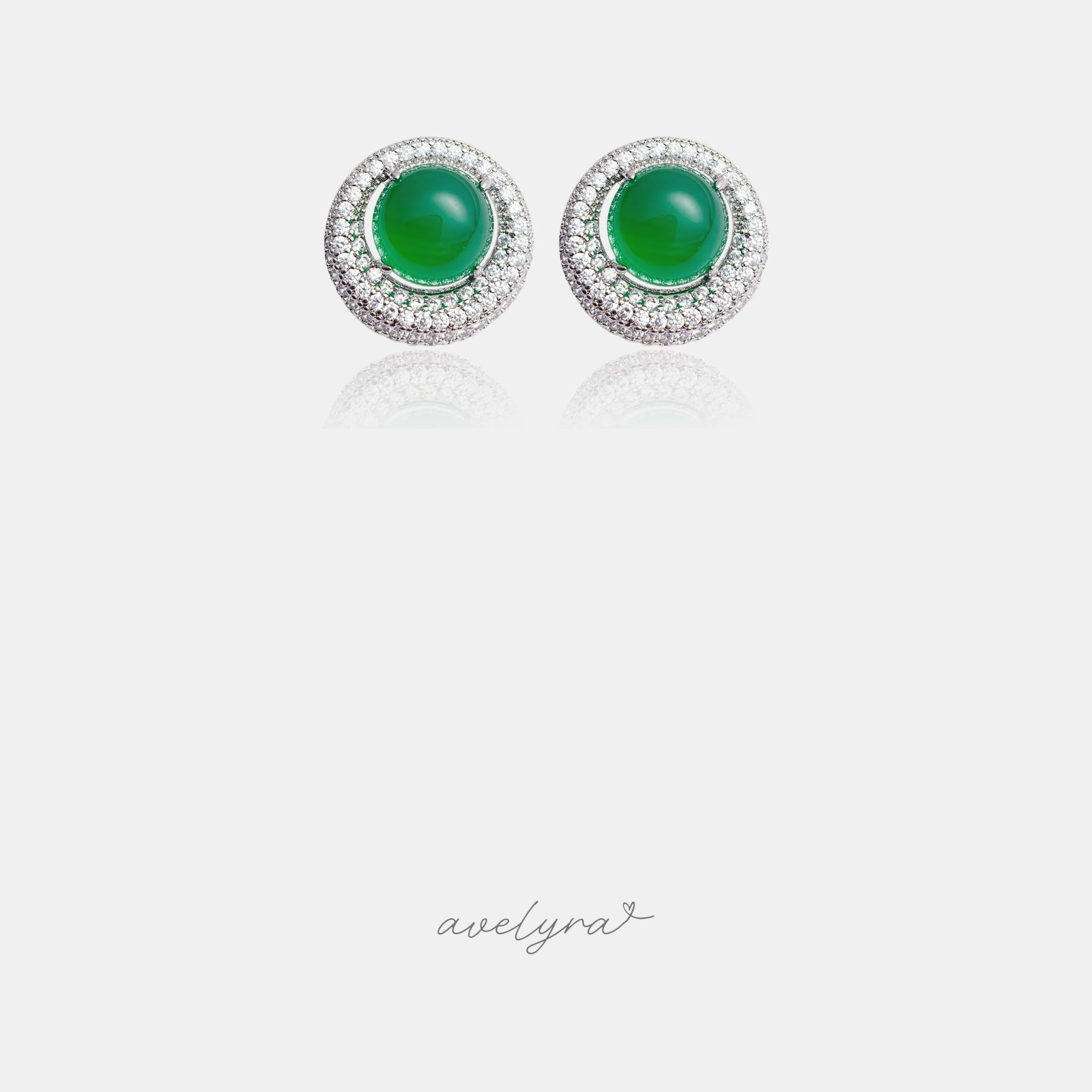 Silver-tone round stud earrings with a green cabochon centre surrounded by two rings of clear stones.