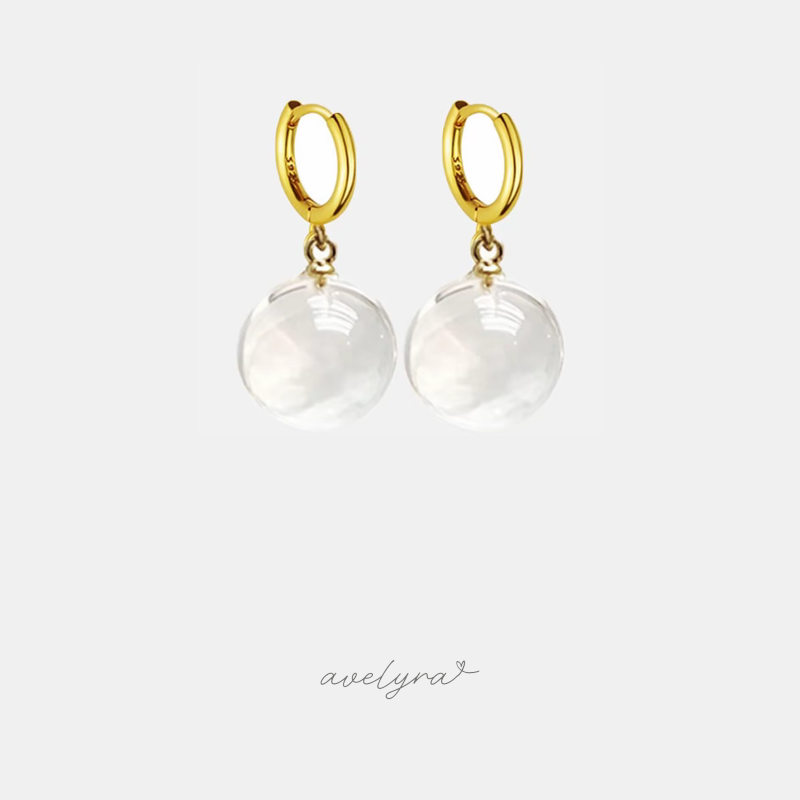 Gold-tone huggie hoop earrings with clear round glass sphere drops.