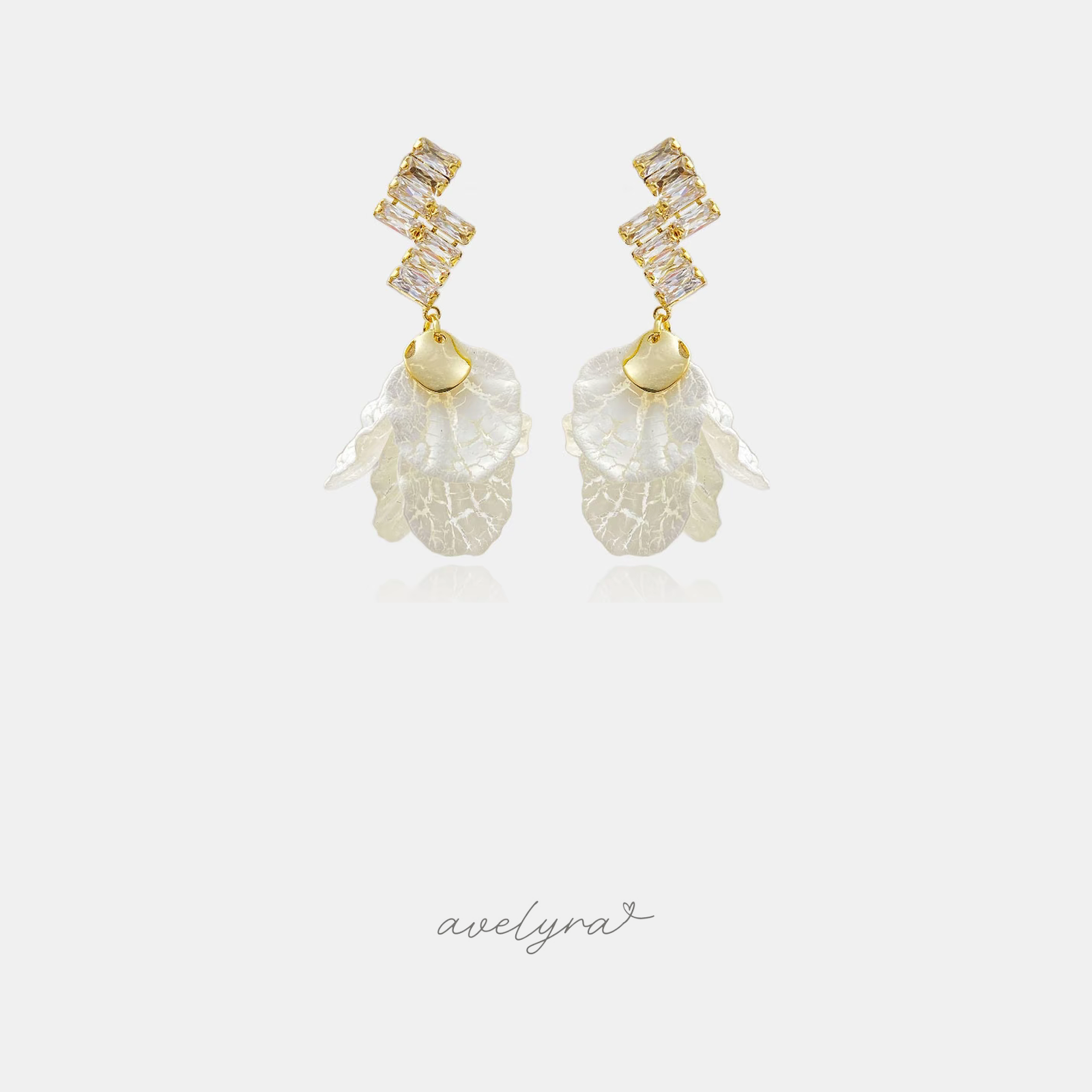 Gold-tone dangle earrings with clear baguette crystals and frosted ivory veined petal clusters.