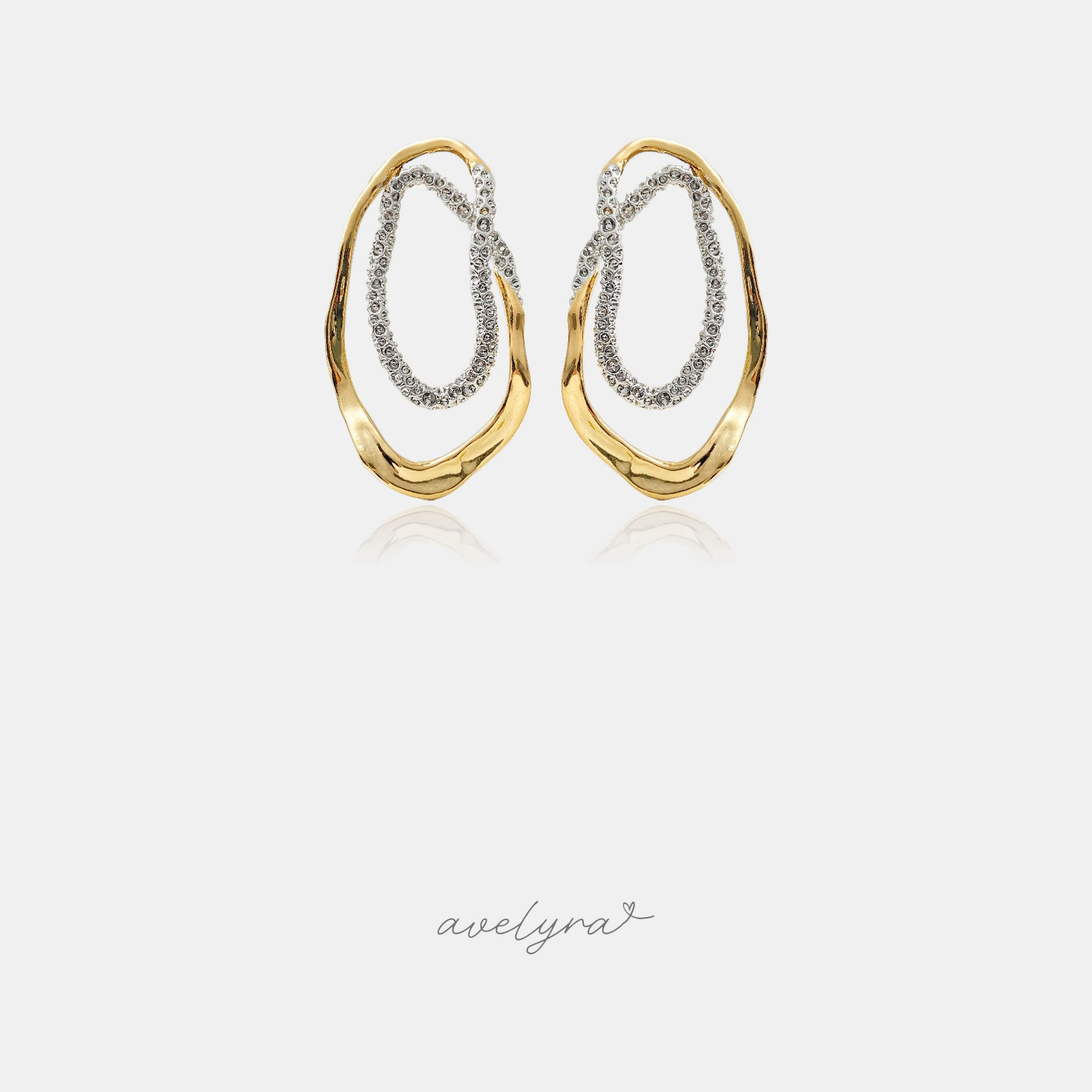 Interlocking organic oval hoop earrings in polished gold-tone and crystal pave silver-tone.