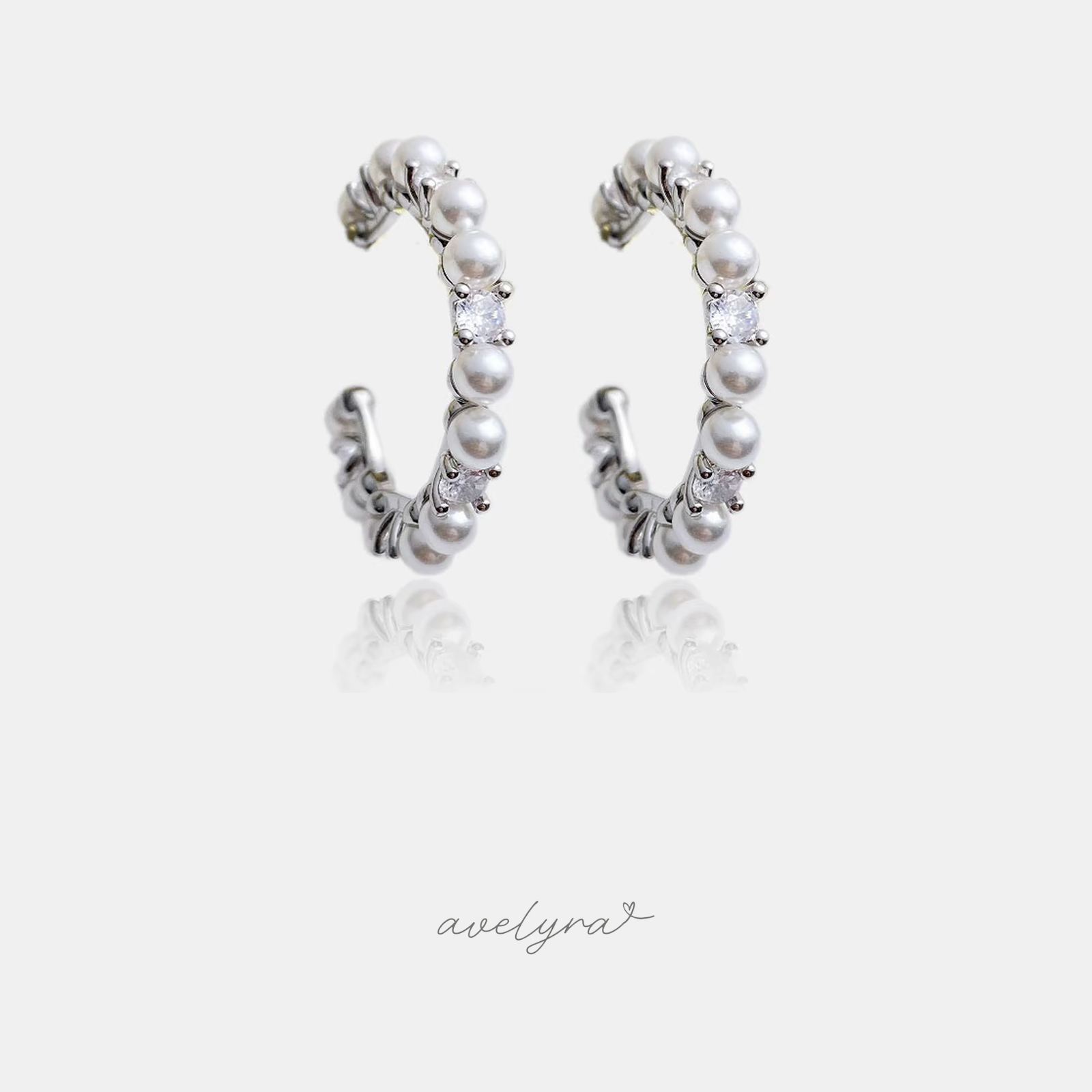 Silver-tone open hoop earrings lined with white pearls and a clear crystal accent.