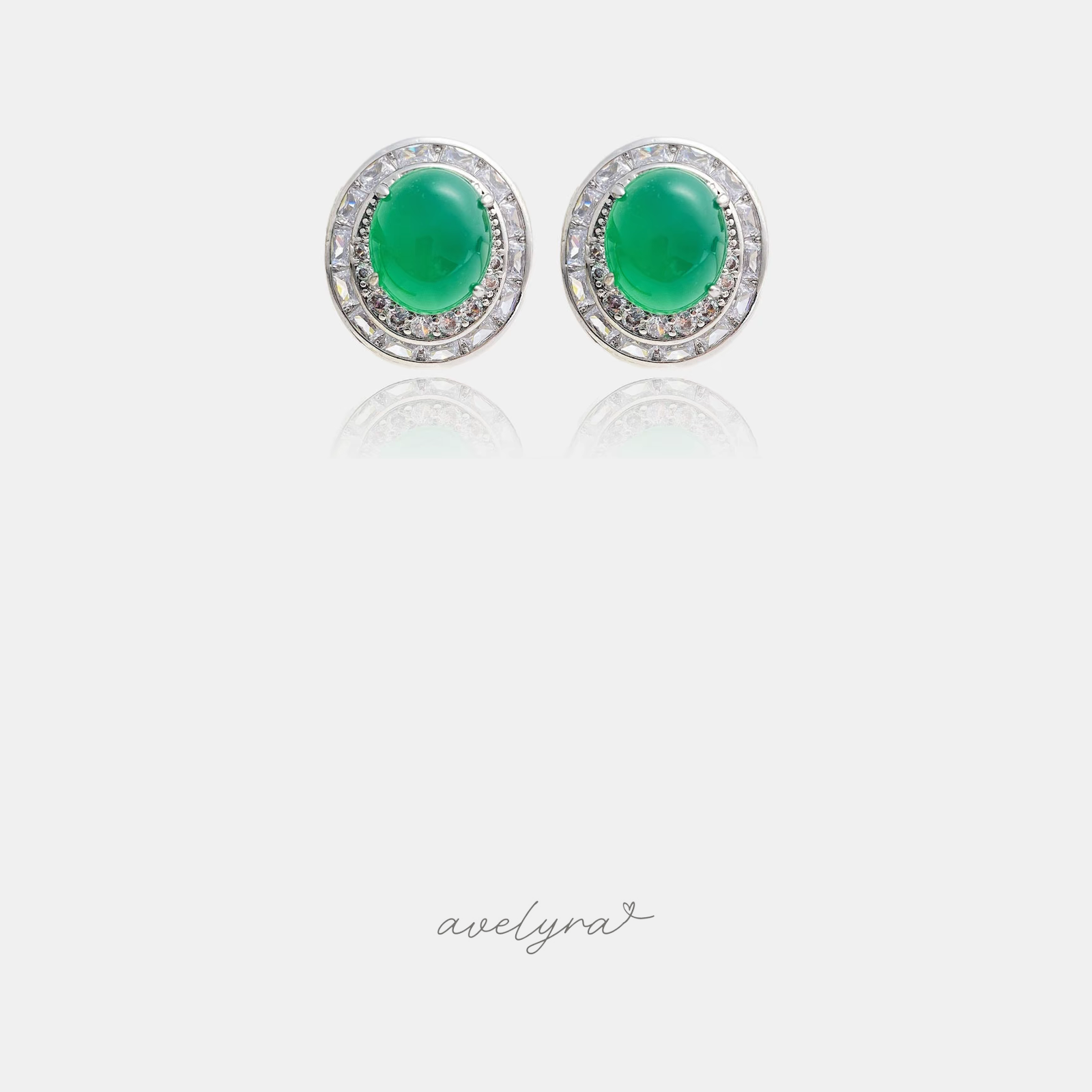 Silver-tone stud earrings with green oval cabochon and a double halo of clear crystals.
