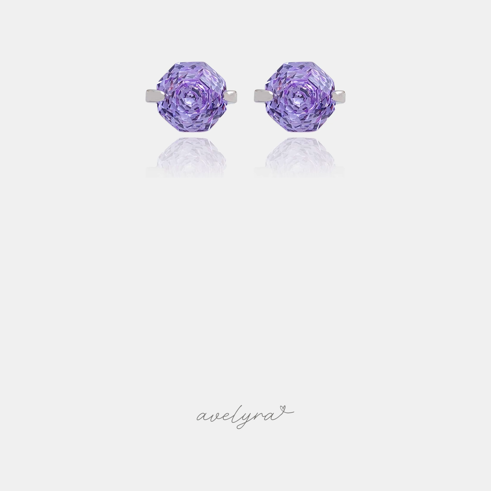 Silver-tone stud earrings each with a single faceted purple stone in a claw setting.