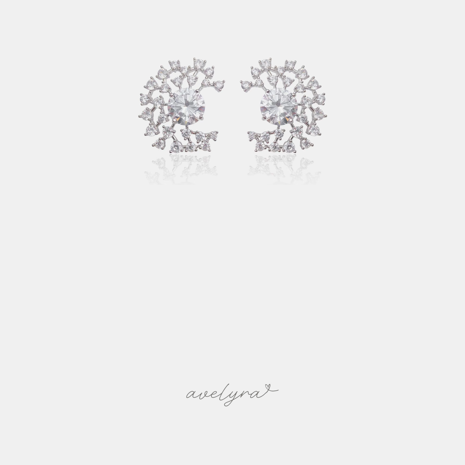 Silver-tone stud earrings with a central round crystal and a fanning cluster of small clear crystals.