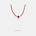 Fine red beaded necklace with a larger central red round bead flanked by small blue beads and gold-tone accent beads.