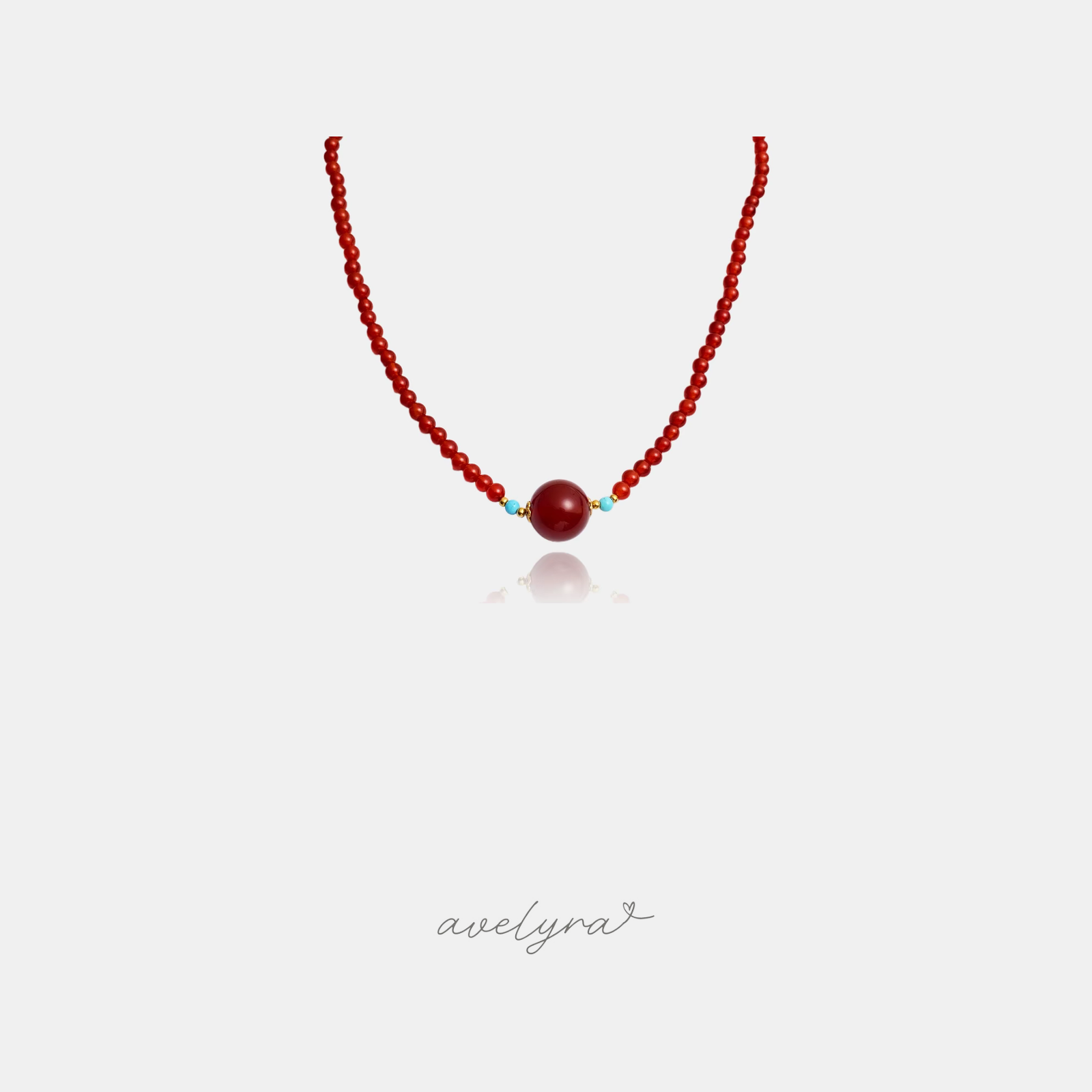 Fine red beaded necklace with a larger central red round bead flanked by small blue beads and gold-tone accent beads.