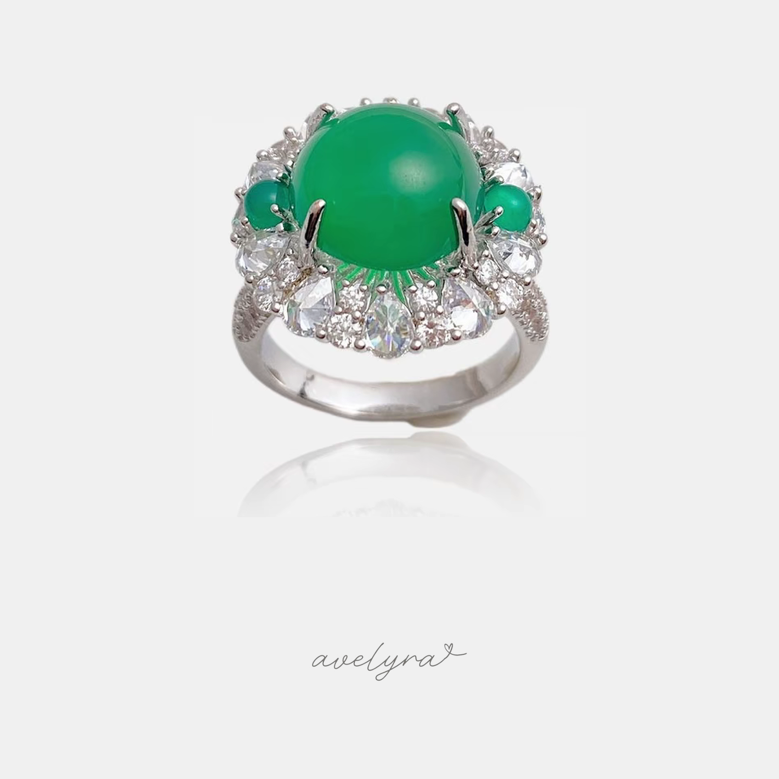 Silver-tone cocktail ring with a large round green cabochon centre framed by clear pear and round stones